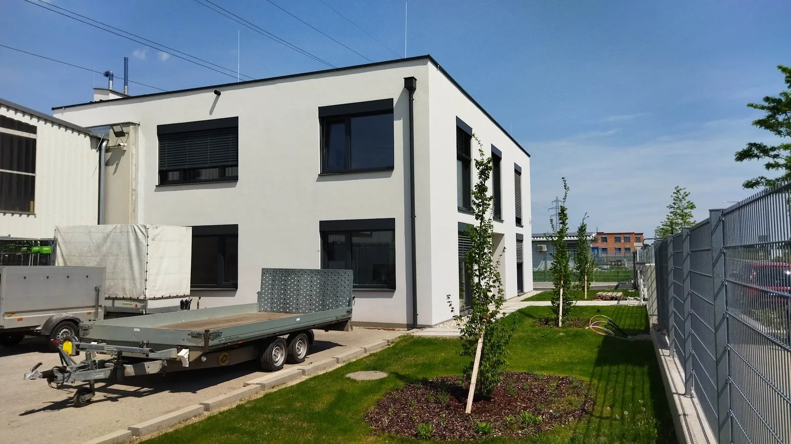 Weißes Gebäude mit Anhängern, Rasen und jungen Bäumen